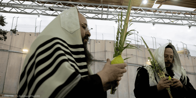 Jewish men with prayer shawls pray in a Sukkah outside the Rachel's Tomb