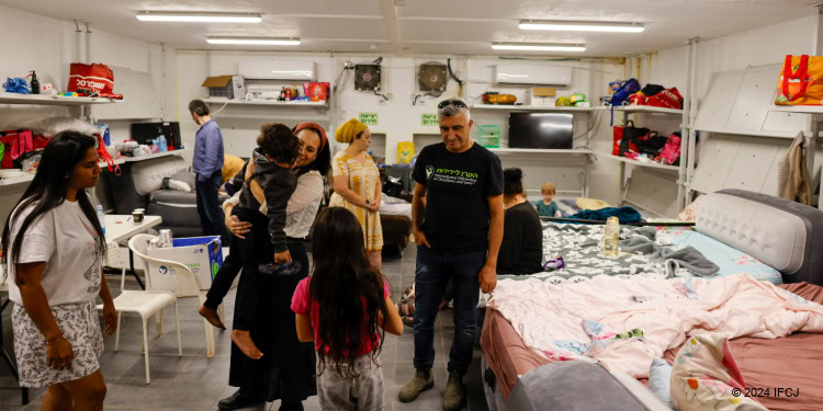 Family in public bomb shelter receiving Fellowship food and emergency aid in response to Hezbollah attacks.
